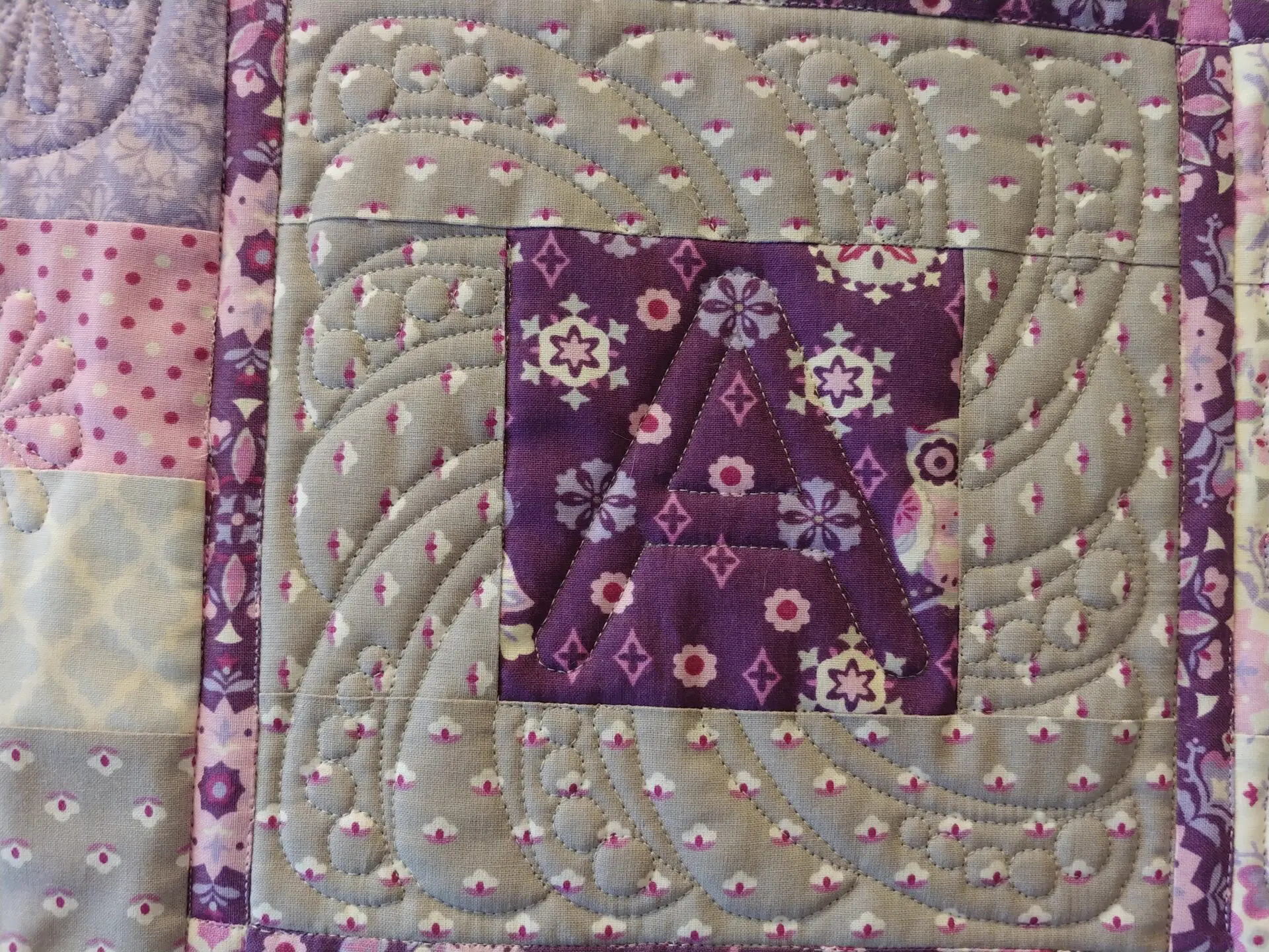 A close up of the purple and green quilt