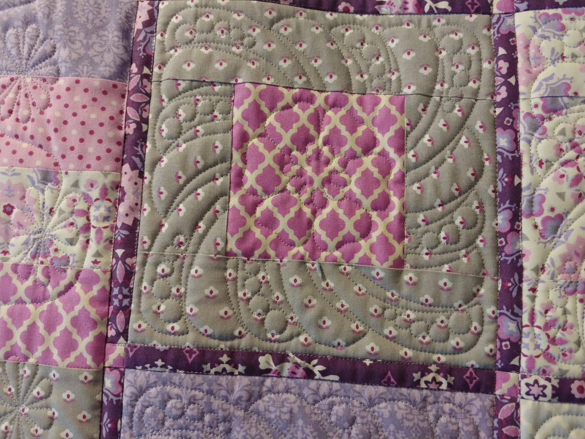 A close up of the quilt with purple and green designs