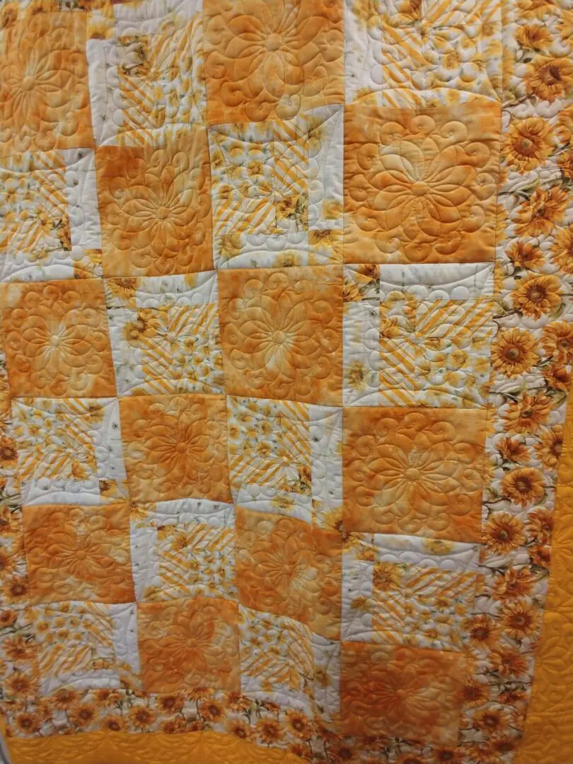 A quilt with orange squares and flowers on it.