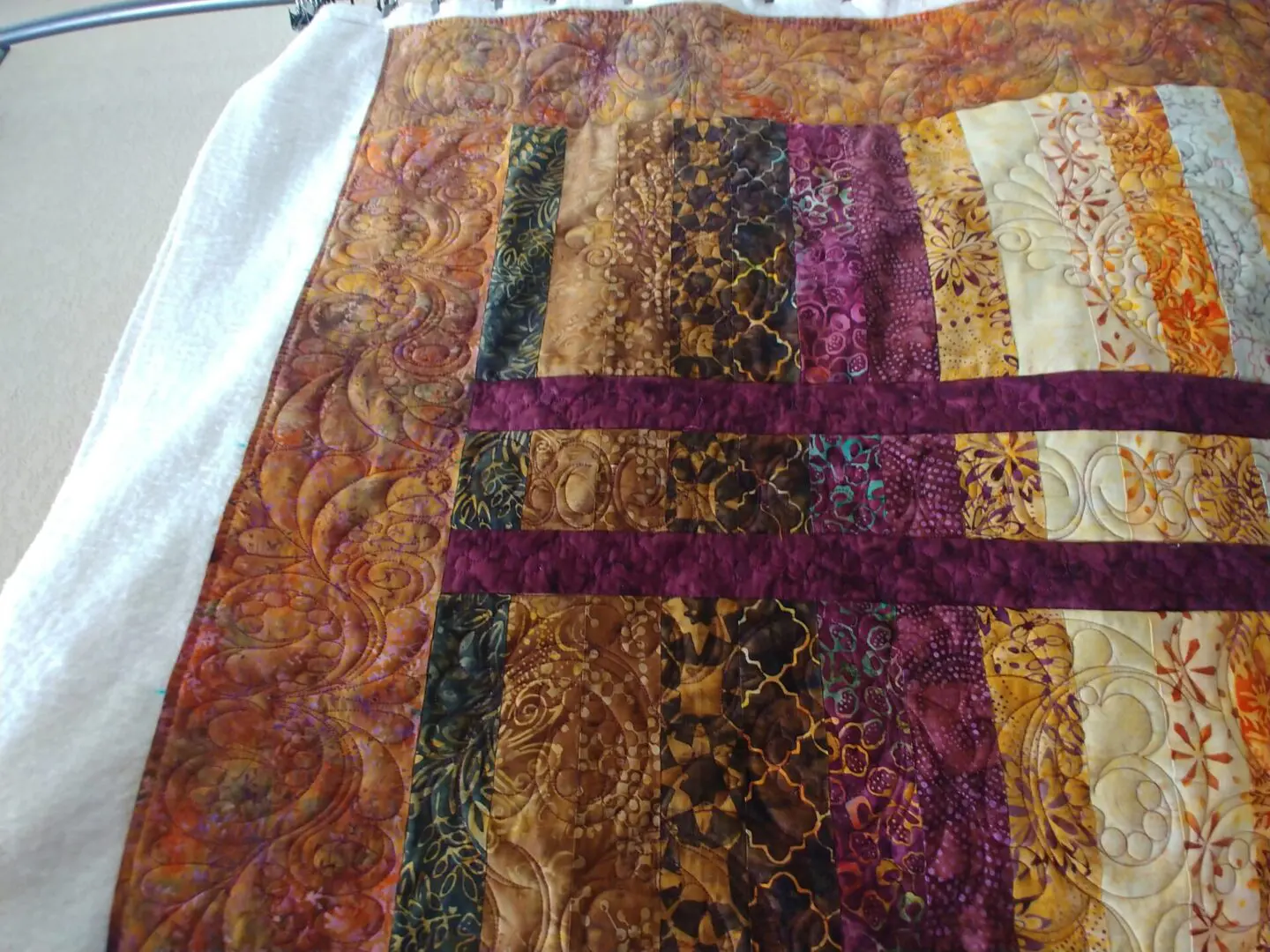 A close up of the quilt with some purple and gold designs