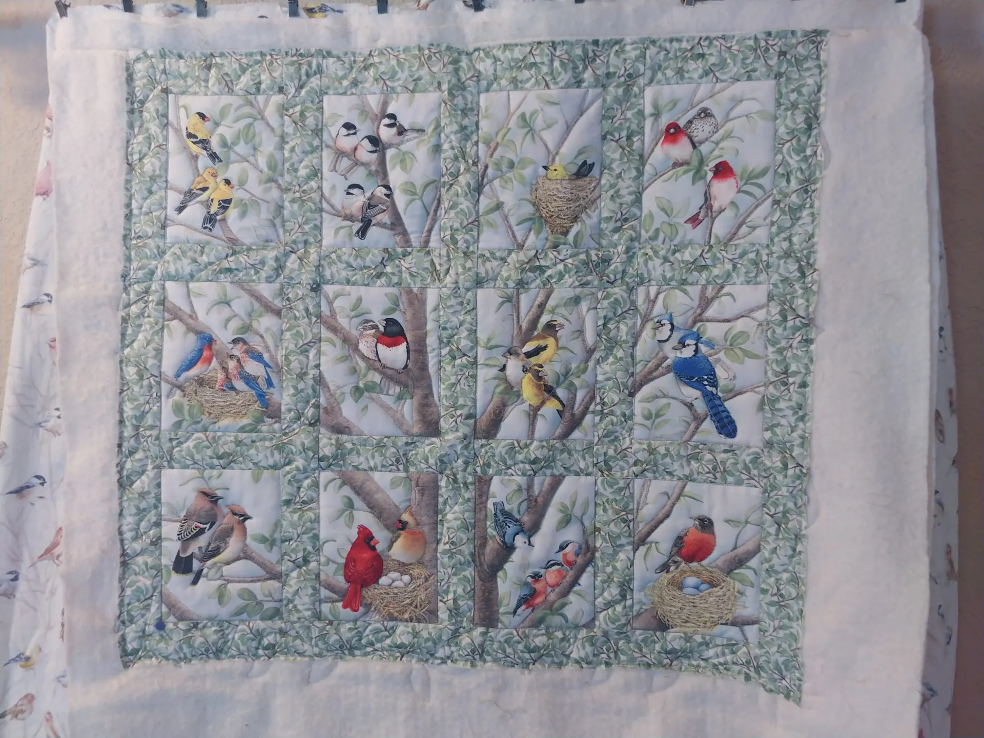 A quilt with birds on it and trees