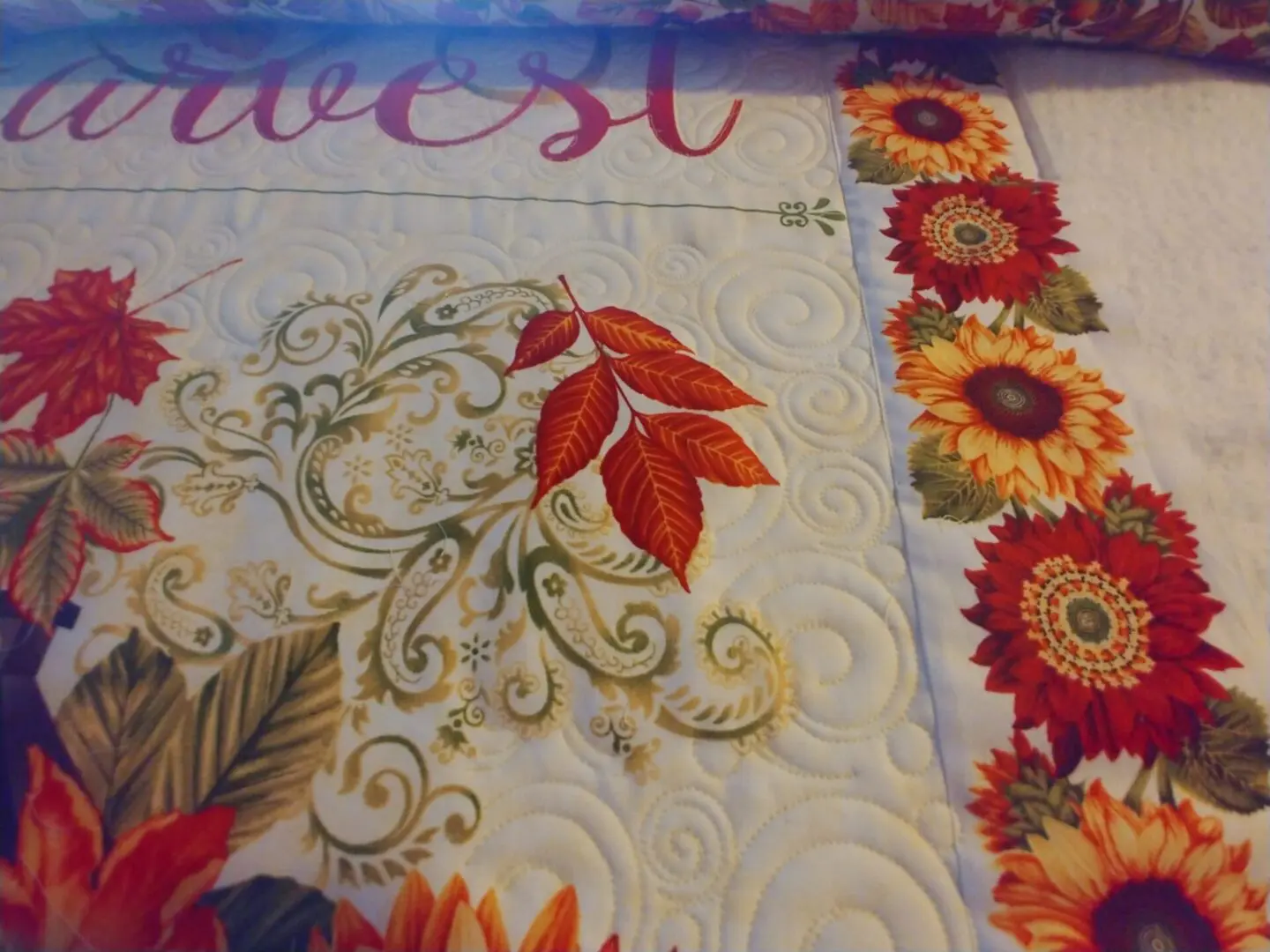 A close up of the leaves and flowers on a quilt