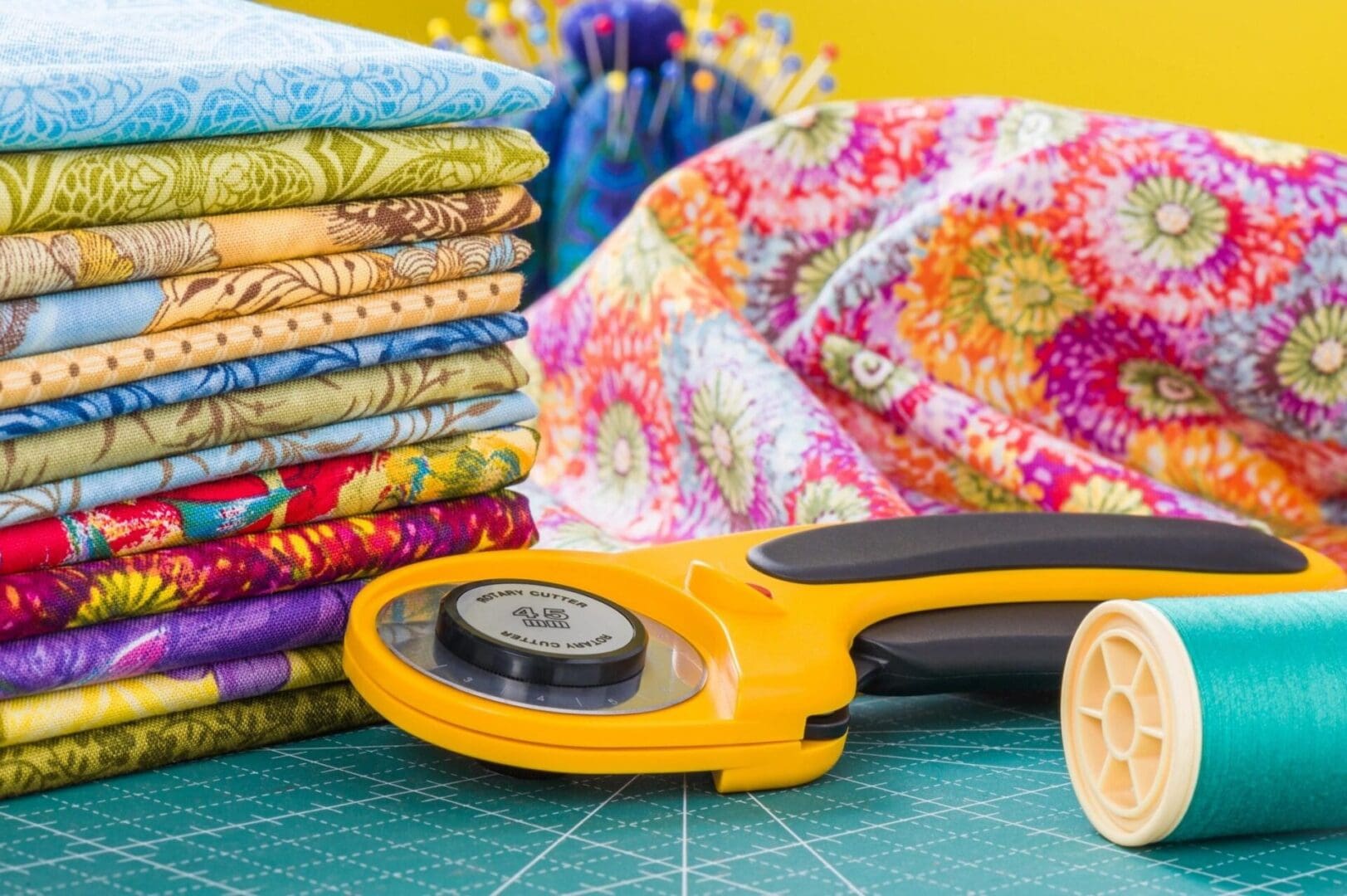 A yellow rotary cutter and some fabric on top of a table.