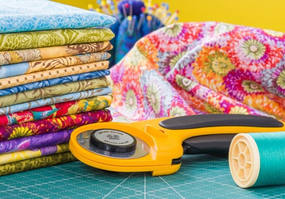 A yellow rotary cutter and some fabric on top of a table.