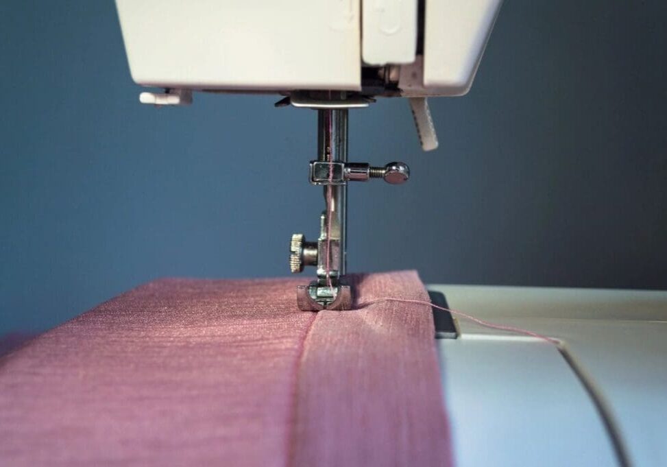 A sewing machine with pink fabric on it.